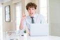 Young business man working with computer laptop at the office pointing finger up with successful idea Royalty Free Stock Photo