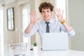 Young business man working with computer laptop at the office showing and pointing up with fingers number nine while smiling