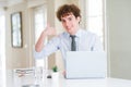 Young business man working with computer laptop at the office smiling doing phone gesture with hand and fingers like talking on Royalty Free Stock Photo