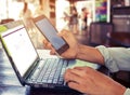 young business man working on his laptop and using smart phone sitting at wooden table in a coffee shop Royalty Free Stock Photo