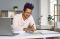 Young business man working on laptop at office, smiling and making calculations Royalty Free Stock Photo