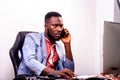 Young business man working in office with laptop and talking on mobile phone Royalty Free Stock Photo