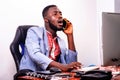 Young business man working in office with laptop and talking on mobile phone Royalty Free Stock Photo