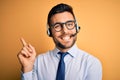 Young business operator man wearing customer service headset from call center with a big smile on face, pointing with hand and Royalty Free Stock Photo