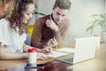 Young business partners people gathered together, discussing creative idea in office. Using modern laptop, having coffee. Royalty Free Stock Photo