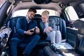 Young business people opening champagne in limo
