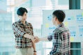Young business people shaking hands Two handsome young men shake hands with smiles at the office with a colleague with a graph in Royalty Free Stock Photo