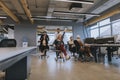 Young business people in smart casual wear having fun while racing on office chairs and smiling Royalty Free Stock Photo