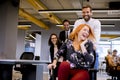 Young business people in smart casual wear having fun while racing on office chairs and smiling Royalty Free Stock Photo