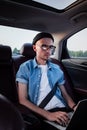 Young business person using laptop on a backseat of a car. Royalty Free Stock Photo