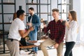 Young business team of five young cheerful multiracial startup coworkers having fun enjoy communication during coffee Royalty Free Stock Photo