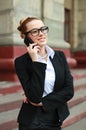 Young business woman in black suit and glasses talking on phone Royalty Free Stock Photo