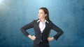 Young business woman in black suit and white shirt is standing, holding her hands on hips. Isolated. Blue background. Royalty Free Stock Photo