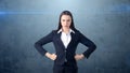 Young business woman in black suit and white shirt is standing, holding her hands on hips. Long-haired girl is serious. Royalty Free Stock Photo