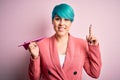 Young business woman with blue fashion hair holding paper plane as travel symbol surprised with an idea or question pointing Royalty Free Stock Photo