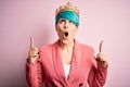 Young business woman with blue fashion hair wearing queen crown over pink isolated background amazed and surprised looking up and Royalty Free Stock Photo