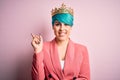 Young business woman with blue fashion hair wearing queen crown over pink isolated background with a big smile on face, pointing Royalty Free Stock Photo