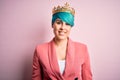 Young business woman with blue fashion hair wearing queen crown over pink isolated background with a happy and cool smile on face Royalty Free Stock Photo