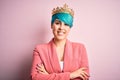 Young business woman with blue fashion hair wearing queen crown over pink isolated background happy face smiling with crossed arms Royalty Free Stock Photo