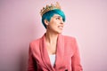 Young business woman with blue fashion hair wearing queen crown over pink isolated background looking away to side with smile on Royalty Free Stock Photo