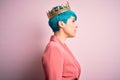 Young business woman with blue fashion hair wearing queen crown over pink isolated background looking to side, relax profile pose Royalty Free Stock Photo