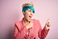 Young business woman with blue fashion hair wearing queen crown over pink isolated background smiling and looking at the camera Royalty Free Stock Photo