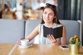 Young business woman in a cafe reading an ebook and drinking coffee