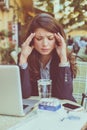 Young business woman at cafe working with head pain.