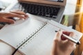 Young business woman in casual dress sitting at table in cafe and writing in calendar notebook