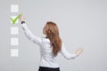 Young business woman checking on checklist box. Gray background. Royalty Free Stock Photo