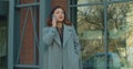 Young business woman in a coat is talking on phone outside near modern office building. Serious business woman with Royalty Free Stock Photo