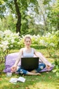 Young business woman doing yoga outside office building sitting in lotus position in the park with her laptop and cup of tea or co Royalty Free Stock Photo