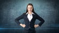 Young business woman dress in black suit and white shirt is standing, holding her hands on hips with copyspace. Royalty Free Stock Photo