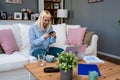 Young business woman freelance expatriate in smart casual working at home in home office using smartphone to check questions on