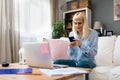 Young business woman freelance expatriate in smart casual working at home in home office using smartphone to check questions on