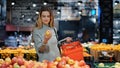 Young business woman girl buyer client blonde lady consumer stands in shop near counter with fruits in grocery store Royalty Free Stock Photo