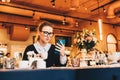 Young business woman in glasses sits in cafe at table, uses smartphone, drinking coffee. Girl working, chatting Royalty Free Stock Photo