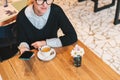 Young business woman in glasses sits in cafe at table, uses smartphone, drinking coffee. Girl working Royalty Free Stock Photo