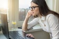 Young business woman with glasses working on laptop computer at home, in hotel, talking on video, working remotely Royalty Free Stock Photo