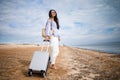 Young business woman with her suitcase luggage on beach view on sunny day. Asian female on ocean shore watching waves. Royalty Free Stock Photo