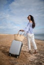 Young business woman with her suitcase luggage on beach view on sunny day. Asian female on ocean shore watching waves. Royalty Free Stock Photo