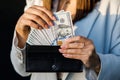 Young business woman hides US dollars in a black wallet, close up of female hands. The concept of cash payments, savings Royalty Free Stock Photo