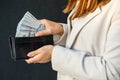 Young business woman hides US dollars in a black wallet, close up of female hands. The concept of cash payments, savings Royalty Free Stock Photo