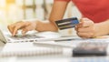 A young business woman holding a blue credit card in hand and using a laptop computer to shop online and dial the number on the Royalty Free Stock Photo