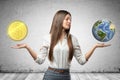 Young business woman holding earth globe and golden dollar coin in her hands on grey wall background Royalty Free Stock Photo