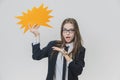 Young business woman is holding a orange speech bubble, which is star-shaped, isolated, on the white background. Young