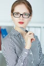 Young business woman holding pen near the face looking in camera portrait.