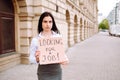 Young business woman holding sign looking for a job wearing black face mask. Unemployment, job search