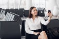 Young business woman at international airport, making selfie with mobile phone and waiting for her flight. Female Royalty Free Stock Photo