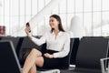 Young business woman at international airport, making selfie with mobile phone and waiting for her flight. Female Royalty Free Stock Photo